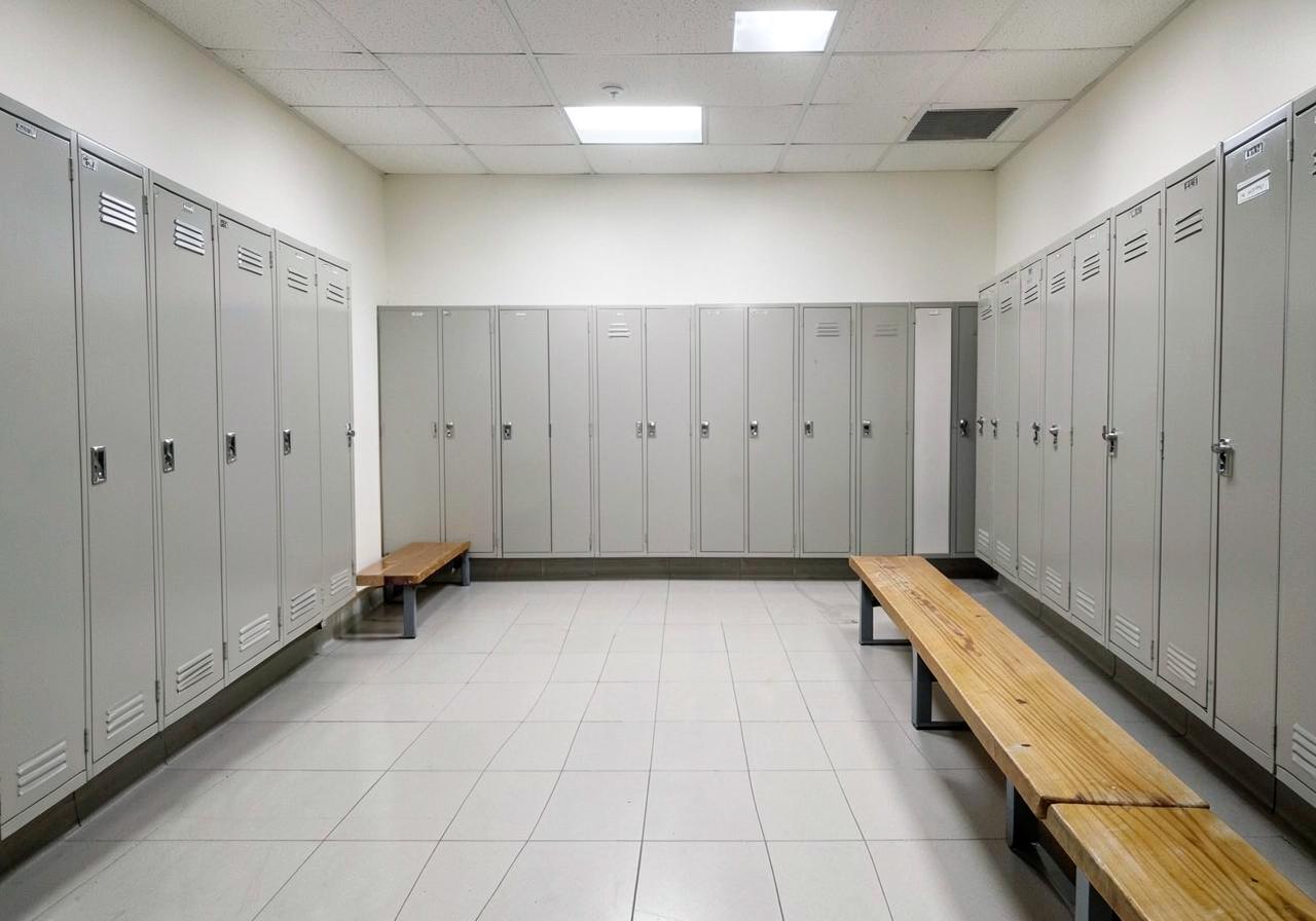 Lege kleedkamer van een sportschool met tegelvloer, banken en gesloten lockers