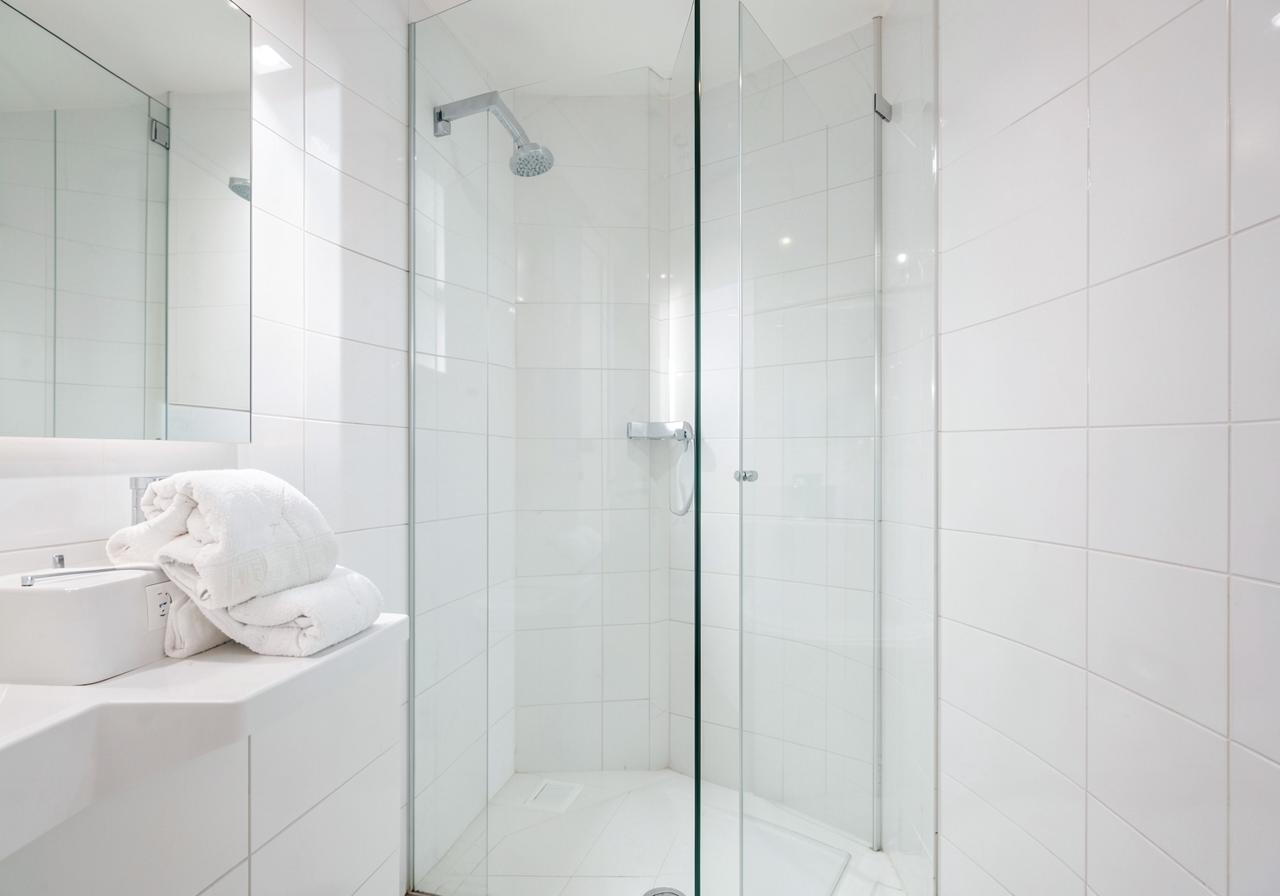 Schone witte hotelbadkamer met glazen douche en opgevouwen handdoeken
