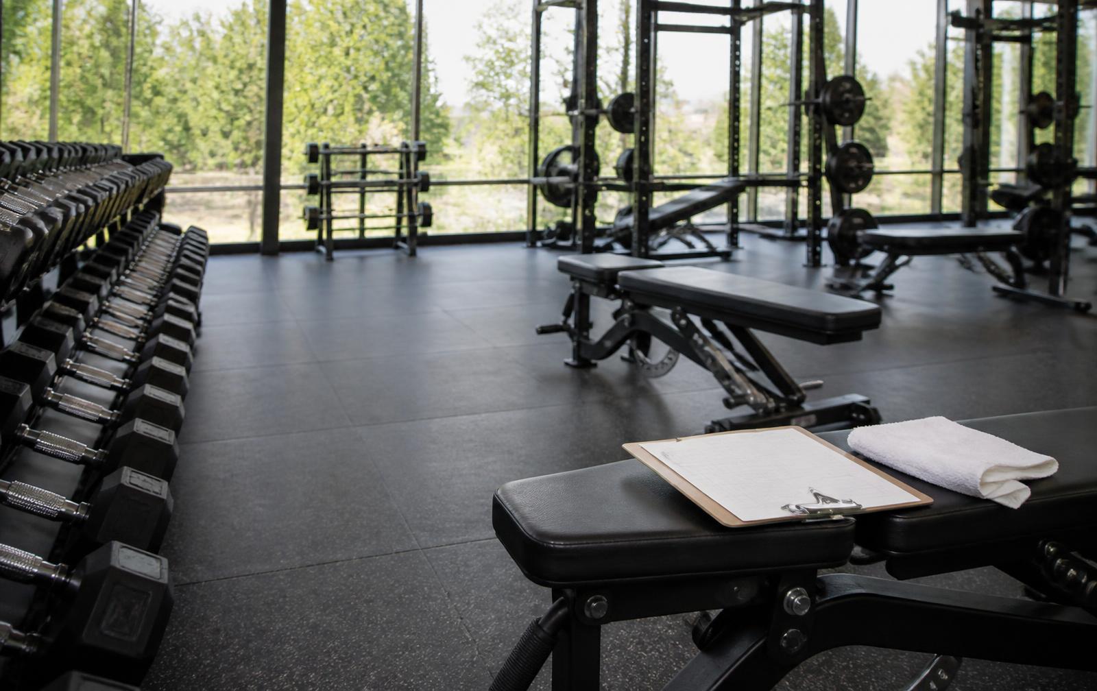 Schone sportschoolvloer met dumbbellrek en een inspectieklembord op een bank